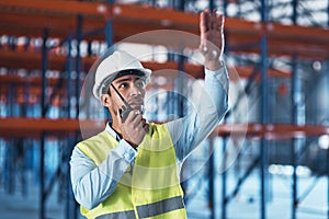 Life that higher. a handsome young contractor standing alone in the warehouse and using a walkie talkie.