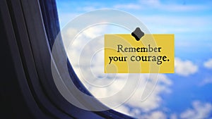 Life inspirational and motivational quote - Remember your courage. Sign on a plane\'s window with bright blue sky background.