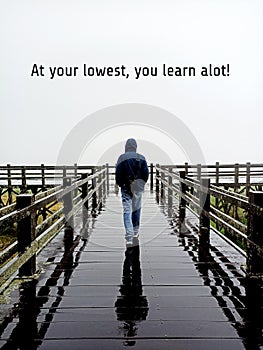 Life inspirational motivational quote - At your lowest you learn a lot. With man and his shadow walking on bridge. photo
