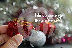 Life inspirational quote - Life is a precious gift. Use your days wisely. With person holding red gift box in hand. photo