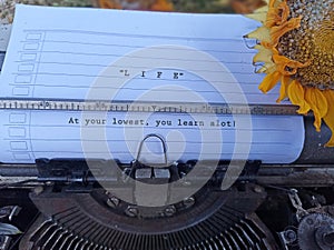 Life inspirational quote - At your lowest, you learn a lot! With typewriting text on white line paper on an old retro typewriter