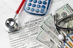 Life insurance application form with banknote and stethoscope