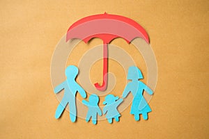 Life insurance concept. Paper cutout of family father, mother, son and daughter under red umbrella on paper background.