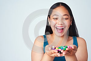 Life just got a little bit sweeter. Studio shot of a cute young girl holding a handful of colorful jelly beans.