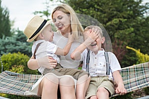 Life moment of happy family!Young mother and two beautiful sons ride on the swings