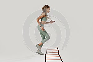 Life is movement. Full length shot of young sportive mixed race woman in sportswear training on agility ladder drill