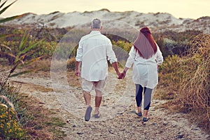 Life is a path best travelled together. a mature couple going for a relaxing walk on the beach.