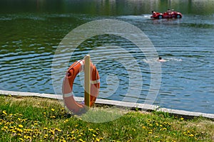 Life preserver on the shore of the lake in the background swimming people