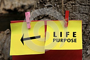 Life purpose with direction sign message on yellow paper notes hanging on wooden wall. Find your life purpose concept.
