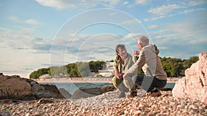 life in retirement, happy old spouses relax on shore near sea during joint vacation