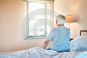 Life in a retirement home. an unrecognizable senior man sitting alone on the edge of his bed in a nursing home.