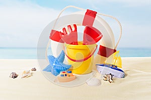 Life ring and beach toys in sand on blue