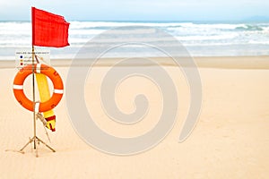 Life saving objects with red flag on beach.