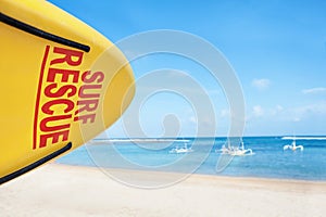 Life saving yellow board with surf rescue sign on beach