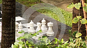 Life size outdoor chess pieces stand at the ready among tropical foliage and palms.