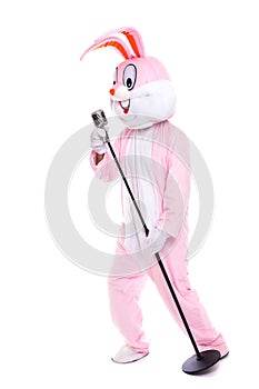 Life size rabbit costume or easter bunny sings in retro microphone. Funny musician singer have fun with Elvis microphone