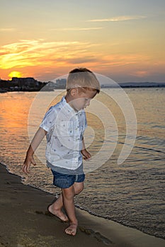 Life style happy childhood, child redhead little boy walking on the beach by the sea at sunset, beautiful coast in Bulgaria