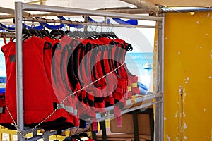 Life vests hanging on a rack. Red lifejackets for watersport activity
