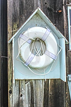 The life you save - a floatable lifesaving device, dirty and grungy, hangs in a little wooden house-like holder on the unfinished