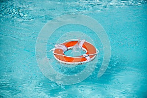 Lifebelt on sea or pool. Orange inflatable ring floating in blue water. Life buoy for protect and safety drowning.