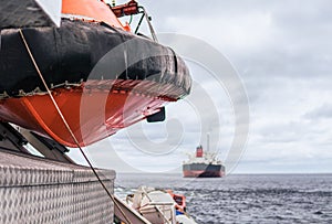 Lifeboat or FRC rescue boat in the vessel at sea. Tanker ship is on background