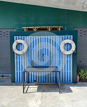 Lifebuoy on blue door and table at outdoor. Funny face for design.