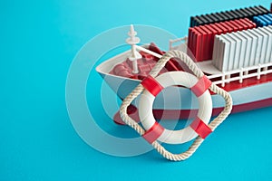 Lifebuoy with containers ship on blue background with copy space. Marine cargo shipment or freight insurance in global shipping