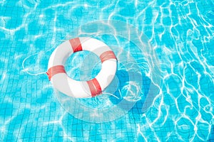 Lifebuoy floating on blue swimming pool.