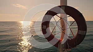 Lifebuoy hanging on the background of the sea at sunrise. Morning at the sea
