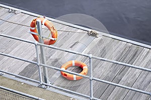Lifebuoy orange ring on sea pontoon for water safety at marina