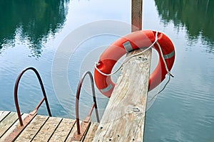 Lifebuoy on a pier of a forest lake on a cloudy day in summer