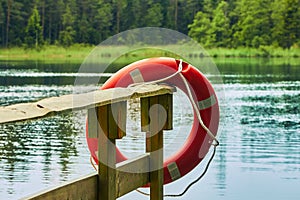 Lifebuoy on a pier of a forest lake on a cloudy day in summer