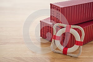 Lifebuoy with red containers on wooden table background with copy space. Marine cargo shipment or freight insurance in global