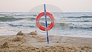 Lifebuoy Ring Hanging on Pole at Seaside Beach on Windy Day with Rough Sea High Waves