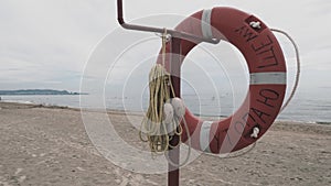 Lifebuoy on a sandy beach. Orange circle on a pole to rescue people drowning in the sea. Rescue point on the shore. Sky