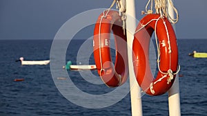 Lifebuoys hang on the pier in the sea swaying on the waves of the boat