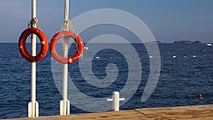 Lifebuoys hang on a pole in the sea, people are bathing