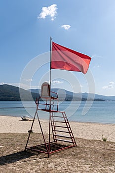 Lifeguard chair with red flag waving. No swimming concept