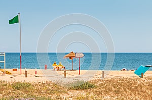 Lifeguard dressed in yellow sitting on a chair on the beach