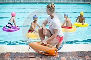 Lifeguard holding rescue can while children swimming in pool photo