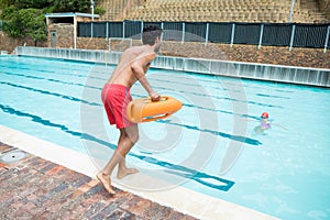 Lifeguard jumping into a swimming pool to rescue drowning boy