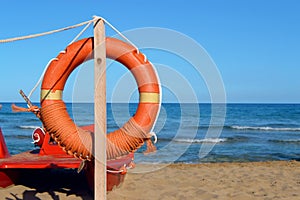 Lifeguard lifebuoy by the sea. People Rescue Equipment. Service for rescue. Tree with orange life jacket on the beach by the sea