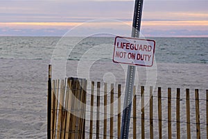 Lifeguard not on duty sign against gray ocean at sunset photo