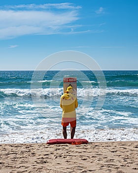 Lifeguard putting in place a warning sign on the beach