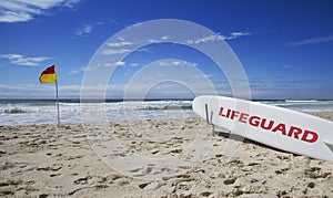 Lifeguard surfboard and safe flag at beach