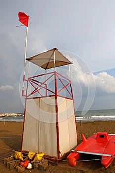 Lifeguard tower on the beach with the red flag fluttering in the