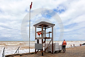 Lifeguard tower and lifeguard in an orange vest on the shore during a storm