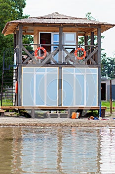 Lifeguard tower for rescue baywatch on beach. Wooden house on sea shore on cloudy sky background. Summer vacation and resort.