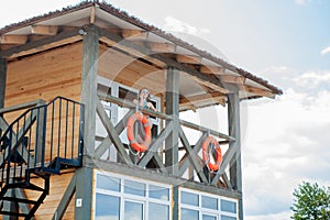 Lifeguard tower for rescue baywatch on beach. Wooden house on sea shore on cloudy sky background. Summer vacation and resort.