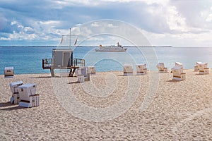 Lifeguard tower on sandy beach on the island of Sylt, Germany with ship on ocean